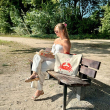 Afbeelding in Gallery-weergave laden, Duurzame tas gerecycled katoen sfeerfoto met model buiten op bankje bij het strand